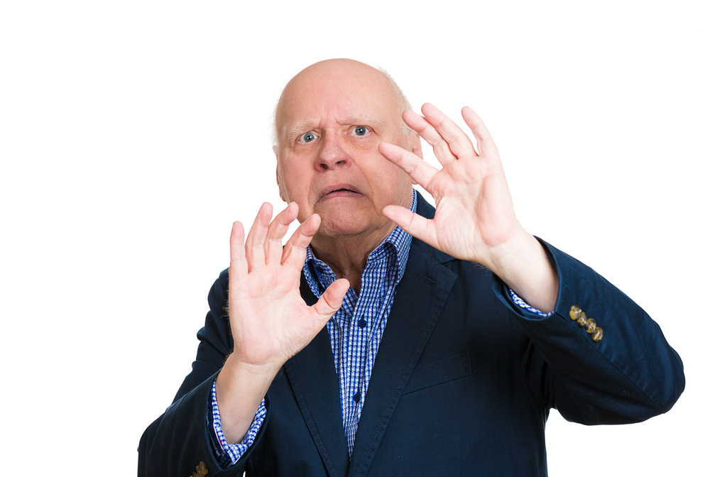 Closeup portrait, senior mature man, looking shocked, scared trying to protect himself in anticipation of unpleasant situation, isolated white background. Negative emotion facial expression feeling